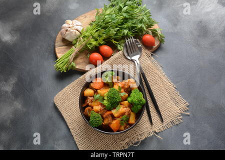 Traditionelle hausgemachte Ungarische Rindfleisch Eintopf, Gulasch mit Kartoffeln, Karotten, Tomaten, Brokkoli in eine Schüssel geben. Stockfoto