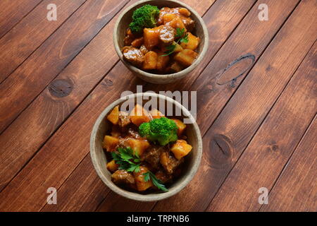 Traditionelle hausgemachte Ungarische Rindfleisch Eintopf, Gulasch mit Kartoffeln, Karotten, Tomaten, Brokkoli in eine Schüssel geben. Stockfoto