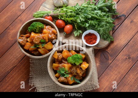 Traditionelle hausgemachte Ungarische Rindfleisch Eintopf, Gulasch mit Kartoffeln, Karotten, Tomaten, Brokkoli in eine Schüssel geben. Stockfoto