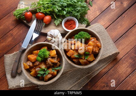 Traditionelle hausgemachte Ungarische Rindfleisch Eintopf, Gulasch mit Kartoffeln, Karotten, Tomaten, Brokkoli in eine Schüssel geben. Stockfoto