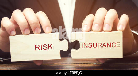Geschäftsmann sammelt Puzzles aus Holz mit dem Wort Versicherung. Die Übertragung bestimmter Risiken an die Versicherungsgesellschaft. Banken und Kreditinstitute Risiken. Bu Stockfoto