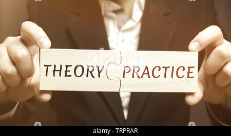 Ein Geschäftsmann sammelt Puzzles aus Holz mit dem Wort Theorie und Praxis. Die Beschaffung von Informationen und die Anwendung in der Praxis. Erste Erfahrungen. Psy Stockfoto