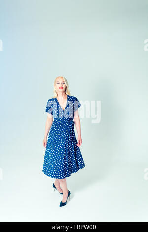 Studio Portrait von schöne blonde Frau in einem dunkelblauen Kleid gegen Weiße einfachen Hintergrund Stockfoto