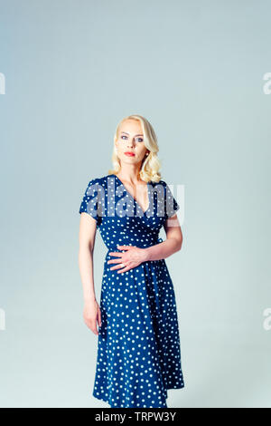 Studio Portrait von schöne blonde Frau in einem dunkelblauen Kleid gegen Weiße einfachen Hintergrund Stockfoto