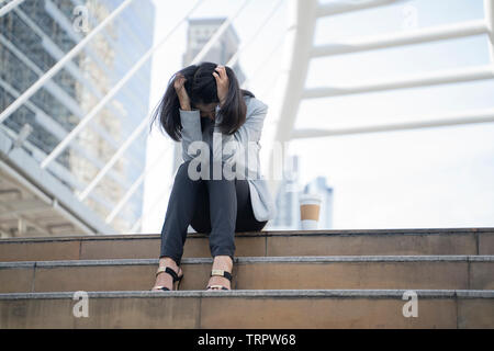 Verzweifelt Geschäftsfrau auf Linie sorgen, nachdem Arbeitslose an der Treppe mit ihren Händen in den Kopf. - Bild Stockfoto