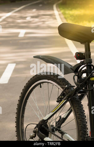 Fahrrad auf einem Radweg im Wald mit Sonnenstrahlen. Travel Concept, Sport und Tourismus, Reise auf dem Fahrrad. Bokeh Hintergrund Stockfoto