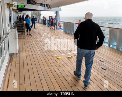 Passagiere Shuffleboard spielen auf dem Deck der TUI Kreuzfahrtschiff Marella Explorer, Nordsee, Europa Stockfoto