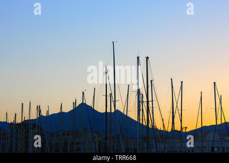 Masten der Yachten in einer Bucht am Mittelmeer Resort geparkt auf dem Hintergrund der Berge in der Dämmerung Himmel Stockfoto