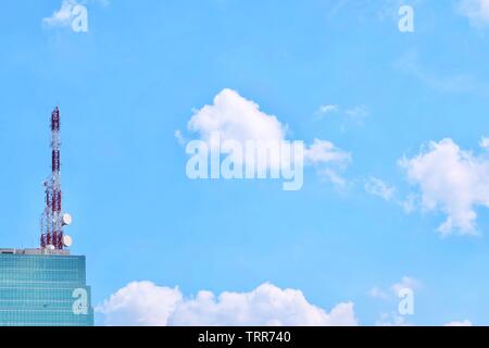Kommunikation Turm und Utility Pole auf dem Gebäude mit elektrischen Leitungen gegen blauen Himmel. Suchen nach Ansicht von Unten. Stockfoto