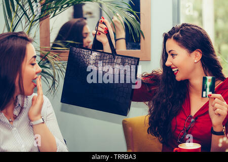 Zwei junge Frauen ihre neue Käufe Austausch miteinander. Sie Kaffeepause nach dem Einkaufen. Konsum, Shopping, Lifestyle Konzept - Bild Stockfoto