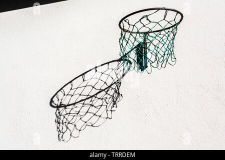 Abstrakte Sicht eines Hoop und net Gießen eine große verzerrte Schatten an der Wand. Stockfoto