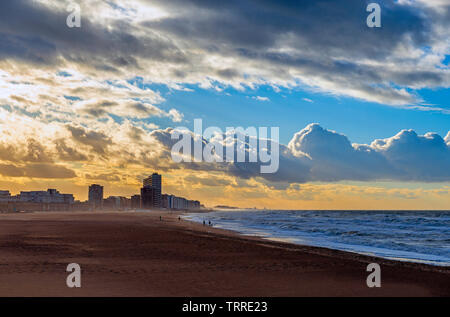 Ferne Silhouetten von Menschen zu Fuß entlang dem Strand von Oostende Stadt bei Sonnenuntergang von der Nordsee, Westflandern, Belgien. Stockfoto