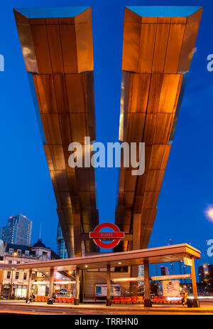 London, England, UK - 28. Mai 2019: Busse fahren unter der markanten auskragenden Dach von Vauxhall Busbahnhof im Süden Londons in der Abenddämmerung. Stockfoto