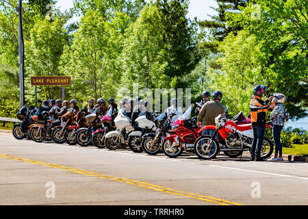 Eine große Gruppe von Motorräder und Fahrer auf der Straße am See angenehm geparkt in den Adirondack Mountains auf einer Tour während Americade 2019. Stockfoto