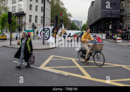 London, England, Großbritannien - 23 April, 2019: ein Radfahrer fährt hinter einem Protest Camp vom Aussterben Rebellion bei Marble Arch in London. Stockfoto