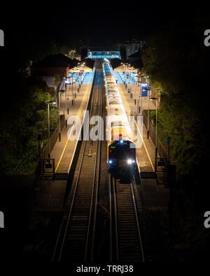 Winchester, England, UK - April 22, 2019: A South Western Railway passenger train Anrufe an der Winchester in Hampshire Bahnhof bei Nacht. Stockfoto
