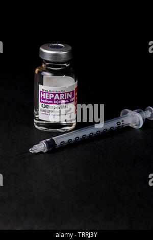 Eine Flasche für das gerinnungshemmende Medikament Heparin Natrium mit einer Spritze auf schwarzem Hintergrund Stockfoto