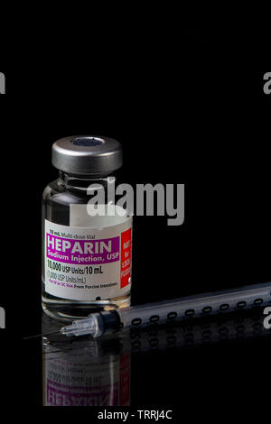 Eine Flasche für das gerinnungshemmende Medikament Heparin Natrium mit einer Spritze auf schwarzem Hintergrund Stockfoto