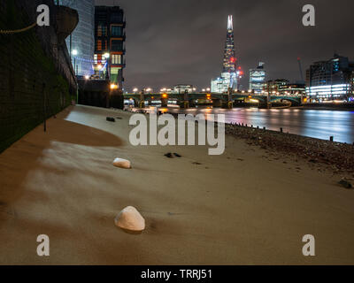 London, England, Großbritannien - 7. März 2019: die Felsen sind auf dem sandigen Ufer der Themse bei Ebbe in Central London links, mit Southwark Bridge und Th Stockfoto