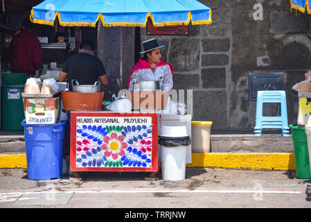 Eine Dame in traditioneller Kleidung verkauft handwerklichen Eis aus ihrem Stall in der Plaza de Armas, Ayacucho, Peru Stockfoto