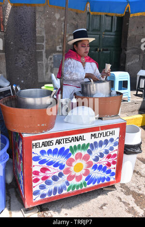 Eine Dame in traditioneller Kleidung verkauft handwerklichen Eis aus ihrem Stall in der Plaza de Armas, Ayacucho, Peru Stockfoto