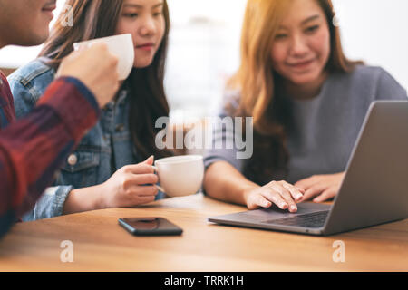 Drei jungen asiatischen Menschen Kaffee trinken während der Verwendung und auf dem gleichen Laptop Computer Stockfoto