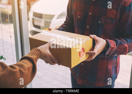 Frauen, die Paketbox Ab Lieferung Mann an der Tür des Hauses Stockfoto