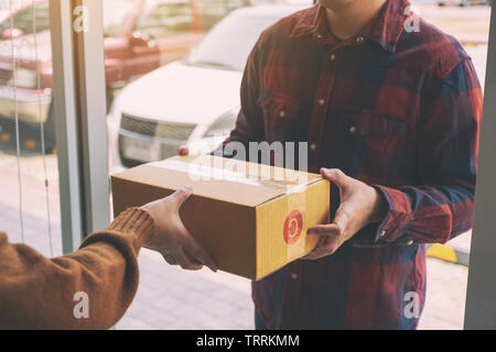 Frauen, die Paketbox Ab Lieferung Mann an der Tür des Hauses Stockfoto