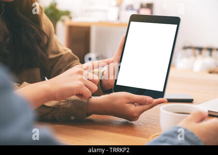 Leute, suchen und gleichzeitig mockup Tablet-PC auf hölzernen Tisch zusammen, Stockfoto