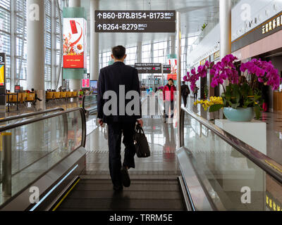 BAIYUN, GUANGZHOU, China - 10 MAR 2019 - Rückansicht des Reisenden im Anzug auf dem Weg zu seinem abfluggate am Internationalen Flughafen Baiyun entfernt. Stockfoto