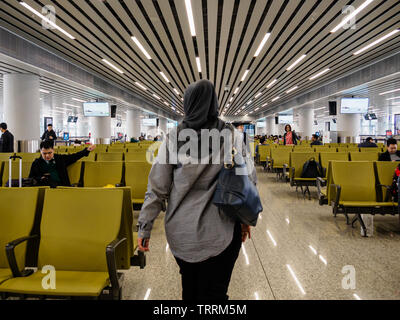 BAIYUN, GUANGZHOU, China - 10 MAR 2019 - Rückansicht einer muslimischen Frau im hijab/Kopftuch geht zu Ihrem Gate am Flughafen Baiyun. China hat eine si Stockfoto