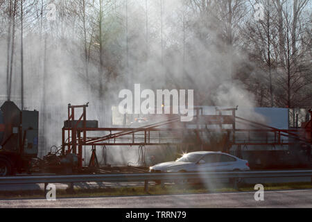 Hameenlinna Finnland 05/04/2016 Die Autobahn ist unter ebnet mit Asphalt. Die asphaltierung Maschinen und Lastwagen sind langsam nach vorn bewegen. Die Luft ist voller Stockfoto