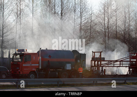 Hameenlinna Finnland 05/04/2016 Die Autobahn ist unter ebnet mit Asphalt. Die asphaltierung Maschinen und Lastwagen sind langsam nach vorn bewegen. Die Luft ist voller Stockfoto