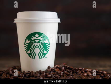 LONDON, UK - Juni 05, 2019: Starbucks Kaffee Pappbecher für nehmen Sie mit Kaffeebohnen auf Holz- Hintergrund. Stockfoto