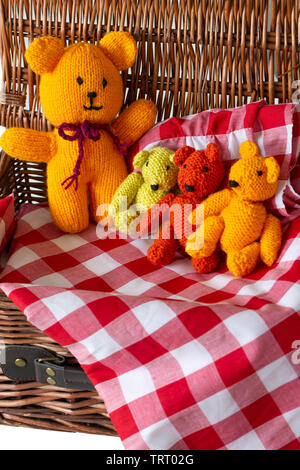 Gestrickter Teddybär Spielzeug auf kariertem Stoff Material in einer Rattan Picknickkorb. Teddybären Picknick Konzept Stockfoto
