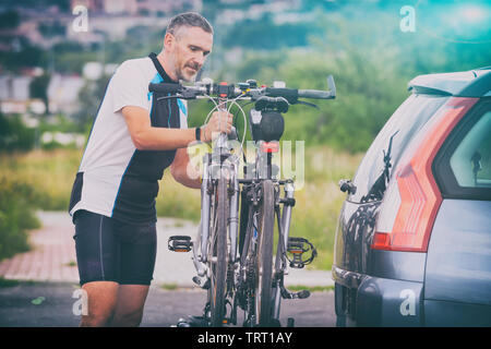 Mann, Sportswear laden Fahrräder auf dem Bike Rack zu einem Auto Anhängerkupplung montiert Stockfoto