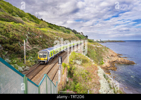 Die Bahn neben Killiney Bay, County Dublin, Irland mit Dublin DART Zug nähert sich Killiney aus dem Norden Stockfoto