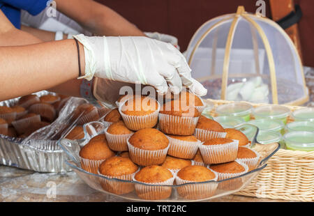 Verkäuferin begradigt Muffins auf Glas Fach während der Prager Botschaft Street Food Festival. Stockfoto
