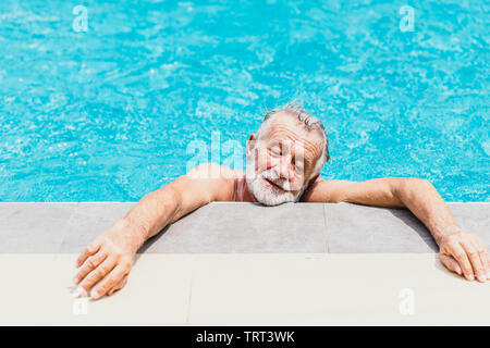 Alter Mann Athlet erschöpft vom Schwimmen an einem heißen Tag im Sommer. Stockfoto