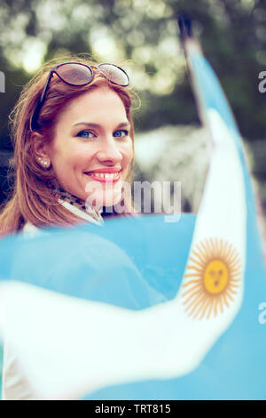 Glückliche junge Frau mit Smile holding Flagge von Argentinien in Park Stockfoto