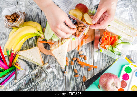 Mutter Cooking School Lunch Box Set, Vorbereitung gesunde Snacks - Käse Sandwich mit Gurke, Karotte. Nüsse, Früchte und Gemüse in Feld. Stockfoto