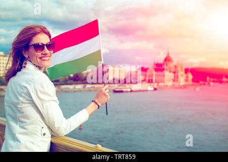 Glückliche junge Frau mit ungarische Flagge bei Sonnenuntergang in Budapest, Ungarn Stockfoto