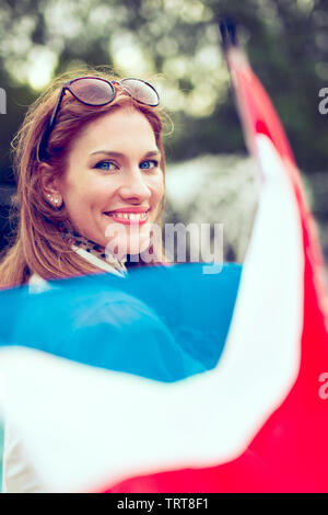 Glückliche junge Frau mit Smile holding Flagge der Niederlande im Park, Schärfentiefe Stockfoto