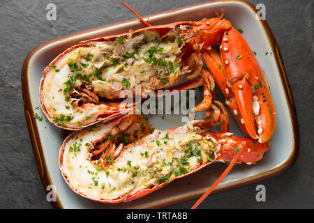 Zwei Hälften eines gegrillten Hummer und Krallen aus einem Hummer Homarus gammarus, in einem Lobster Pot im Ärmelkanal gefangen. Es hat zuerst gekocht, Stockfoto