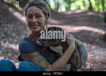 Frau und Hund kuscheln in einem Wald Stockfoto