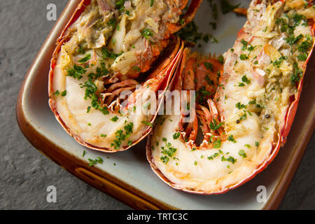 Zwei Hälften eines gegrillten Hummer und Krallen aus einem Hummer Homarus gammarus, in einem Lobster Pot im Ärmelkanal gefangen. Es hat zuerst gekocht, Stockfoto