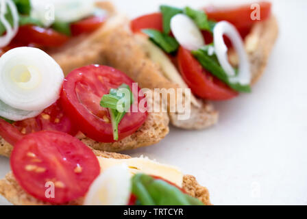 Nahaufnahme der schmackhafte und gesunde Vorspeise von Frühlingszwiebeln und Kirschtomaten und organische Käse mit Basilikum auf gebackenem Brot Stockfoto