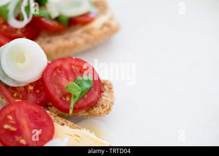 Nahaufnahme der schmackhafte und gesunde Vorspeise von Frühlingszwiebeln und Kirschtomaten und organische Käse mit Basilikum auf gebackenem Brot Stockfoto