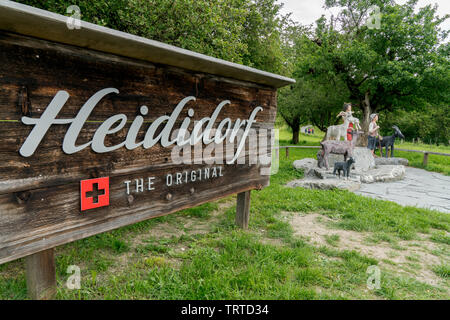 Maienfeld GR/Schweiz - vom 9. Juni 2019: Touristenattraktion unterzeichnen und hölzerne Marionetten der fiktiven Heidi Geschichte in den Schweizer Alpen Dorf Maienf Stockfoto