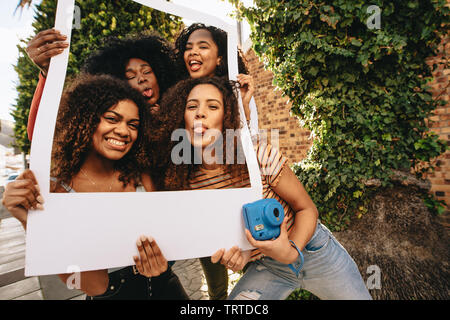 Gruppe von Frauen mit leeren Bilderrahmen. Mädchen lustige Gesichter mit leeren Fotorahmen in der Stadt. Stockfoto